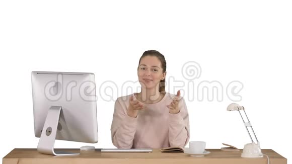 微笑着的千禧一代女人坐在办公桌前对着镜头微笑在白色的背景上交谈视频的预览图