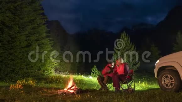 晚上在山上露营时一对情侣在篝火旁闲聊视频的预览图