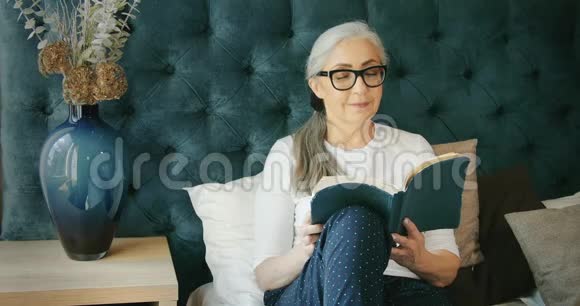 老年妇女在沙发上看书视频的预览图