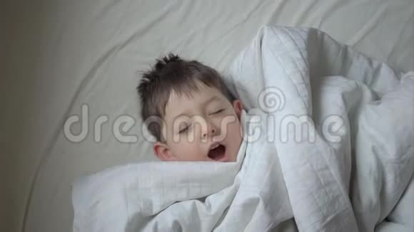 家中躺在床上的可爱小男孩的俯视图视频的预览图