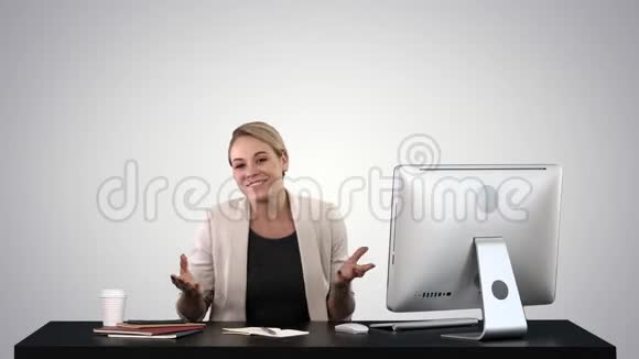 兴奋的商务女性在镜头前交谈坐在桌子上的梯度背景视频的预览图