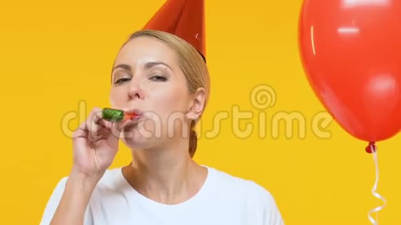 戴着生日帽的滑稽女人拿着气球吹着口哨参加派对视频的预览图