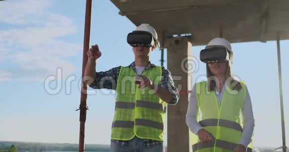 一个男人和一个女人在一个建筑工地的VR眼镜管理着一座建筑的建造讨论着一个视频的预览图