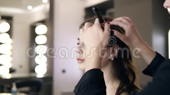 布鲁内特女士用一个大的黑色化妆刷在的脸和脖子上涂上基础或墨粉一个棕色女孩视频的预览图