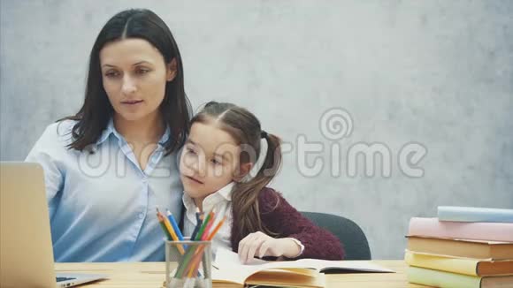 妈妈和女儿坐在桌子旁一起玩个愉快的笔记本电脑关系概念视频的预览图