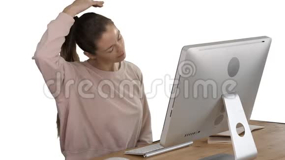精疲力竭的年轻女性坐在家里的办公桌上在白色背景上按摩脖子视频的预览图