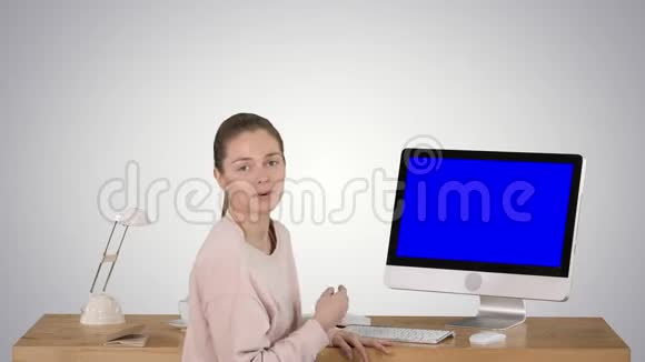 迷人的女人在电脑屏幕上呈现一些东西与摄像机交谈蓝色屏幕模拟显示梯度视频的预览图