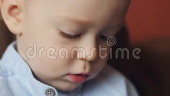 沙发上小男孩的肖像一个小男孩对房间里的东西感兴趣的特写脸视频的预览图