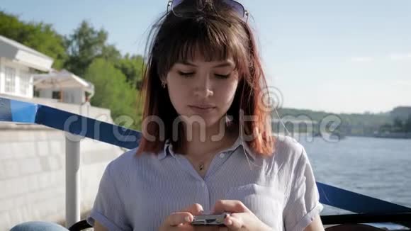 年轻有魅力的高加索女人在河流的背景下使用智能手机应用程序视频的预览图