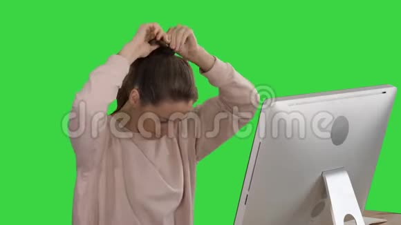 办公室女士穿着粉红色的套头衫带一根毛的尾毛在绿色屏幕上的电脑上工作Chroma键视频的预览图