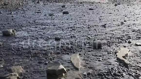早晨的阳光下海水在海滩上的岩石上流动视频的预览图
