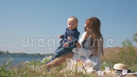 母子关系开朗的女性和小男孩在大自然的家庭野餐中玩耍在草地上亲密无间视频的预览图