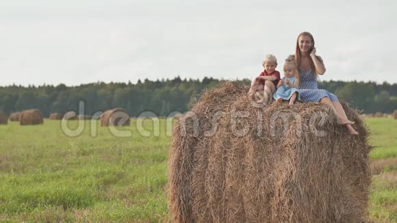 一位母亲带着两个孩子坐在一片稻草堆上视频的预览图