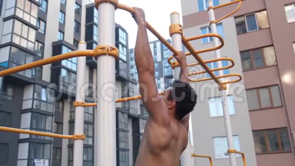 肌肉男在水平杆上做拉力在房子附近的健身区视频的预览图