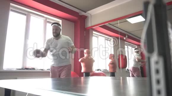 肥胖的白种人留着胡子的人在现代的健身房打乒乓球体重超标动作迟缓友谊视频的预览图