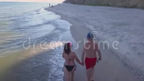 男人和女人在日落时沿着海滩漫步视频的预览图