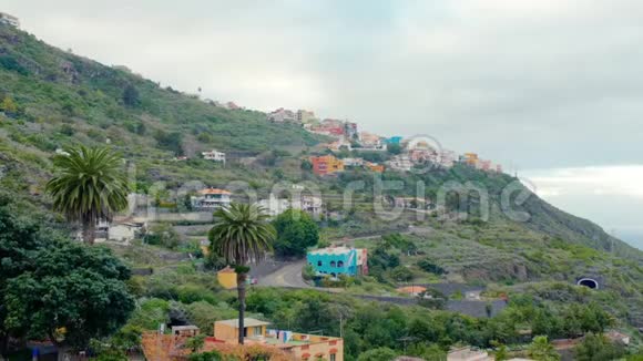 热带景观山谷有茂密的植被和棕榈树背景中的一个小山城视频的预览图