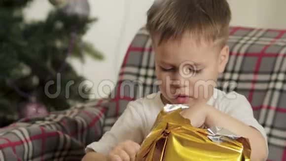 一个小男孩在圣诞树上打开圣诞老人的礼物视频的预览图