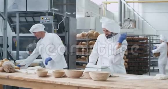有魅力的非常热情的年轻面包师跳舞在一个大的烘焙行业工作同时制作面团视频的预览图
