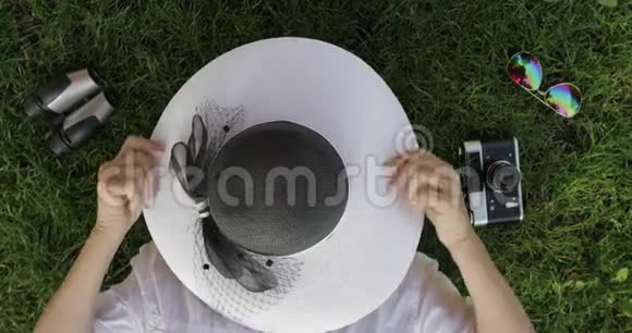 年长的女游客躺在草地上周围是傻瓜脱下来戴上帽子视频的预览图