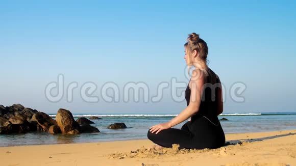 穿运动服的运动女孩在黄色沙滩上冥想视频的预览图