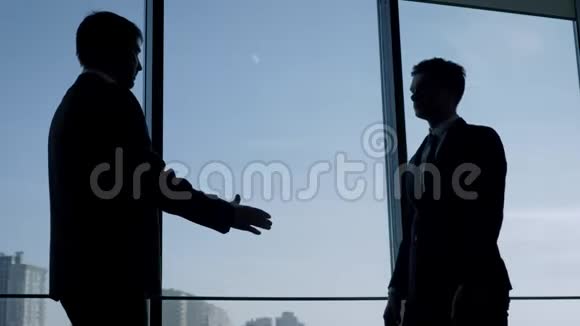 商务人员在办公室的窗口握手互相拍拍肩膀视频的预览图