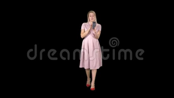 穿着粉色裙子的微笑女人在做视频通话和散步阿尔法频道视频的预览图