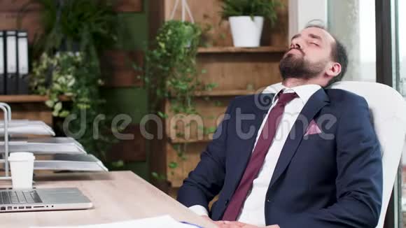 一个穿西装的男人在办公桌前睡着了视频的预览图
