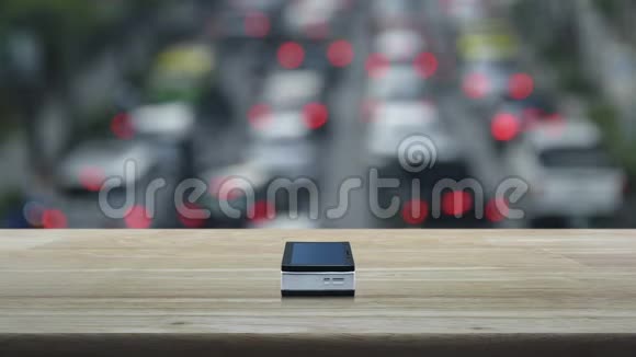 在木制桌子上的现代智能手机屏幕上的银行平面图标在城市的汽车和道路上的高峰时间模糊商业禁令视频的预览图