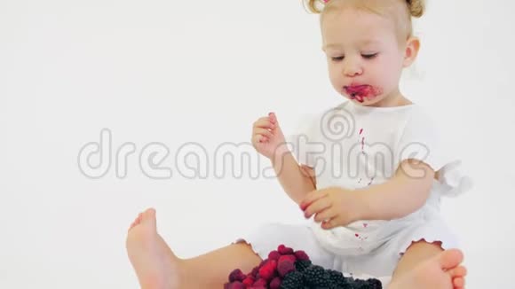 小女孩在白色背景下吃新鲜的覆盆子和黑莓视频的预览图