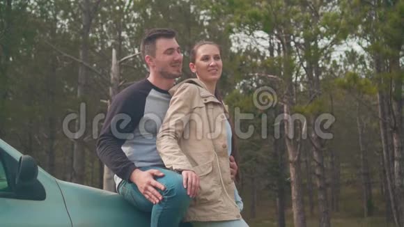 一对年轻夫妇一个男人和一个女孩站在森林里的一辆车上他们在微笑和交谈视频的预览图