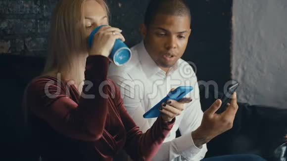 混合种族夫妇使用智能手机在咖啡馆或办公室背景男人和女人交流和使用智能手机视频的预览图