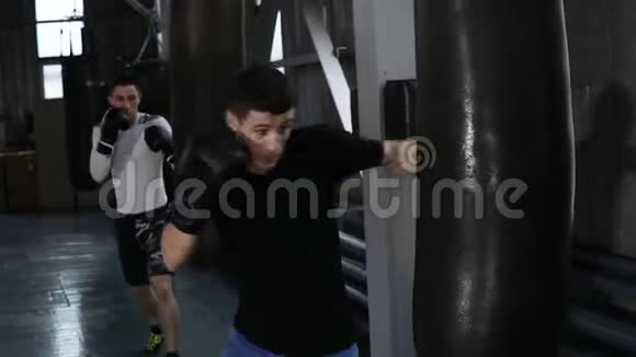 两个身穿便装的男拳击手正在打黑拳梨勤奋训练过程在拳击健身房侧面视频的预览图