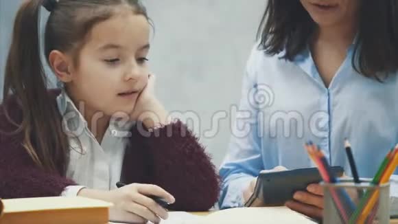 妈妈和女儿指望一个黑色计算器家庭作业在灰色背景下视频的预览图