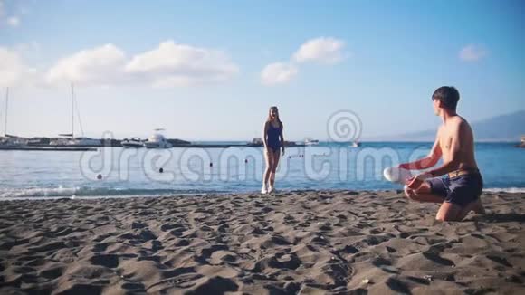 一个年轻人和他的女朋友在海滩上玩飞盘把光盘扔给她视频的预览图