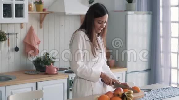 穿着白色浴袍的可爱女孩在厨房里穿着橙色衣服视频的预览图