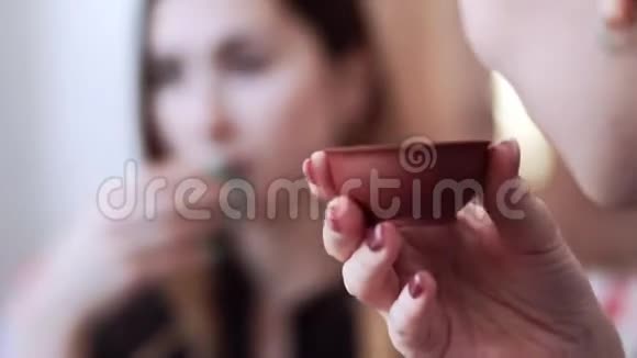 两个白种人的女孩坐着享受小杯子里美味的茶茶道特写视频的预览图