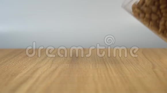 男人手把一堆猫粮从杯子里倒进一张木桌上视频的预览图