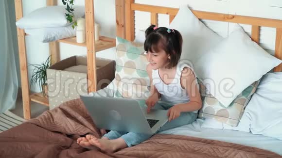 女孩坐在床上用笔记本电脑情绪上说些什么慢动作视频的预览图