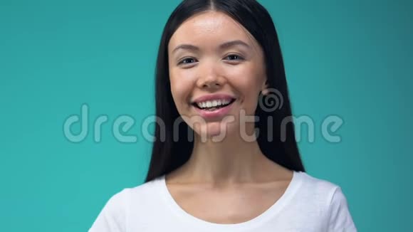 微笑的亚洲女人显示OK手势孤立在蓝色背景确认视频的预览图