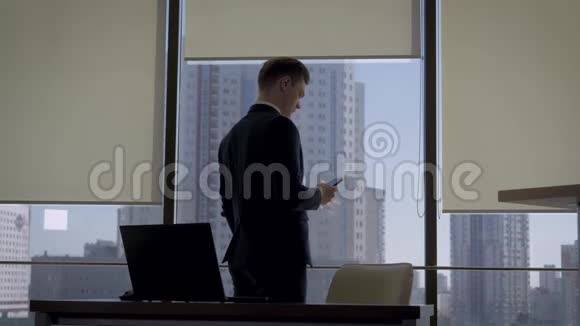 办公室办公室附近的办公室窗户上一位西装革履的办公室主任在打电话视频的预览图