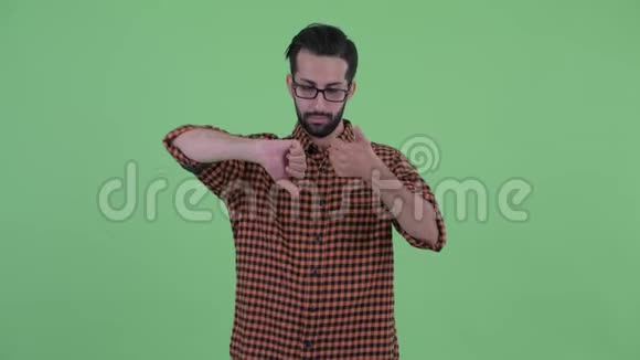 困惑的年轻留胡子的波斯时髦男人在竖起大拇指和竖起大拇指之间做出选择视频的预览图