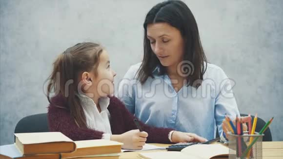 妈妈和女儿指望一个黑色计算器家庭作业在灰色背景下视频的预览图