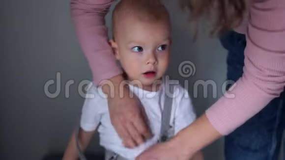 一个母亲的亲密肖像帮助一个两岁的男孩穿衣服幼儿教育幸福家庭视频的预览图