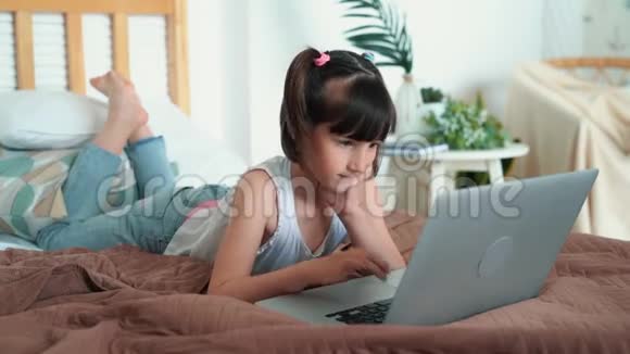 小女孩躺在床上用笔记本电脑按键盘上的按钮慢动作视频的预览图