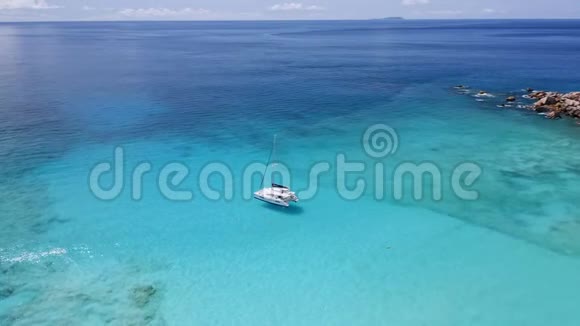 顶级4k无人机白色游艇在宁静的蓝绿色泻湖水域靠近风景如画的热带岛屿视频的预览图