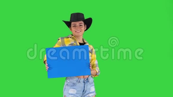 微笑漂亮的牛仔女孩拿着空板在绿色的屏幕上跳舞蓝色的模型视频的预览图