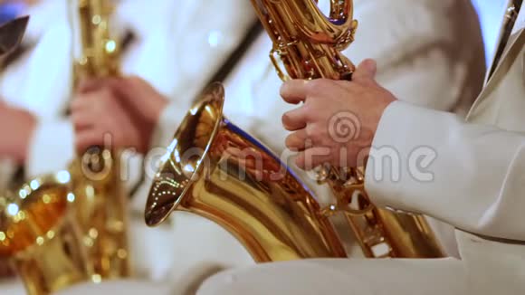 戴着金萨克斯管在爵士乐队里穿着白西装的手特写视频的预览图