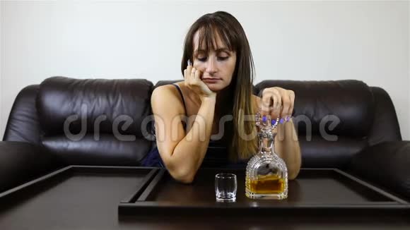 疲惫的女孩倒满了一杯酒倒在桌子上视频的预览图