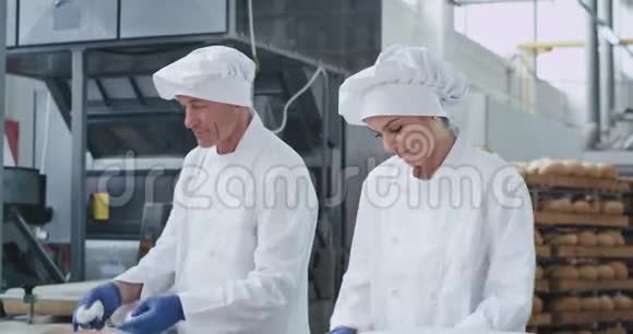 美丽迷人的三个面包师一起工作在一个烘焙行业形成面团烘焙面包视频的预览图